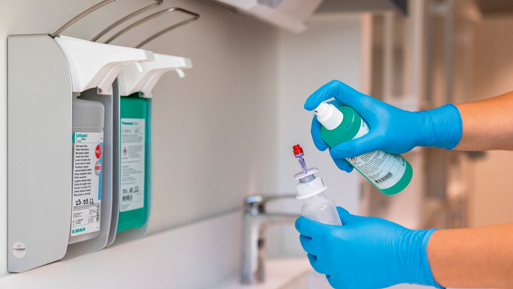 Gloved hands in a veterinary clinic preparing medication, holding a vial and syringe near a medical dispensing device.