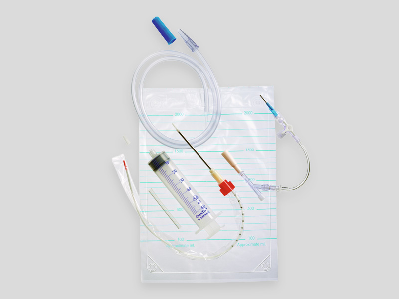 Pleuracan® pleural drainage set with catheter, tubing, syringe, needle, and connectors arranged on a sterile backing, isolated on a light background.