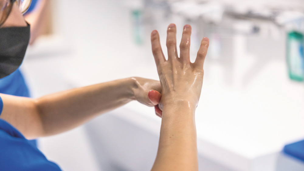 Person rubs hands with disinfectant as part of hand hygiene in a clinical environment.