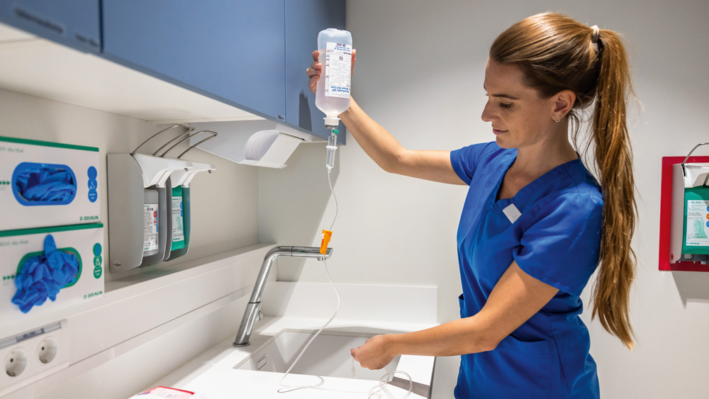 A veterinary professional preparing an infusion setup at a clinical workstation equipped with medical supplies.