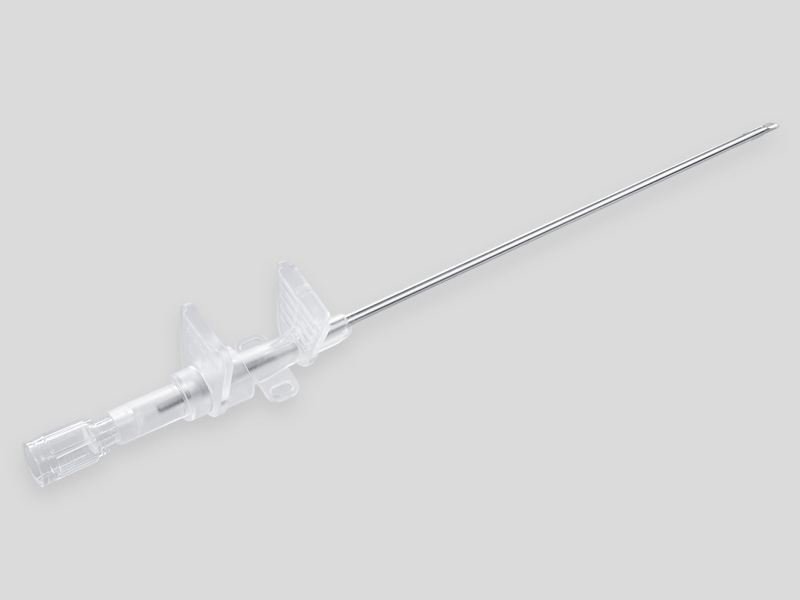 Braunula Vet High Flow intravenous catheter with a long metal cannula and a transparent plastic hub with lateral fixation wings, isolated on a light grey background.