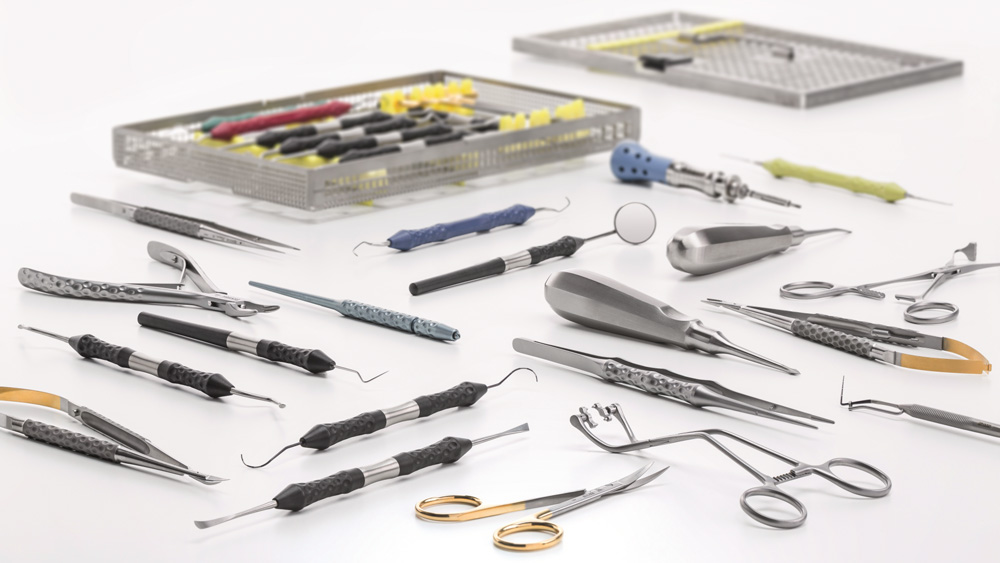 Assortment of dental instruments and tools laid out on a white surface next to an open storage tray.