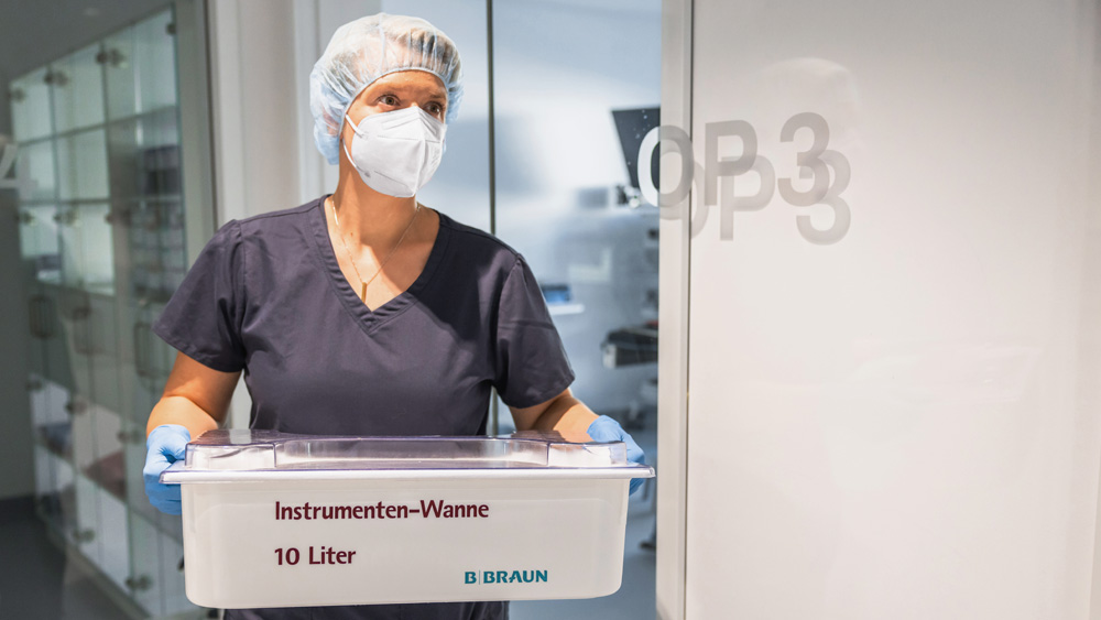 Alt text: Person in technical service clothing handling an Aesculap sterilization container inside a clinical workspace.