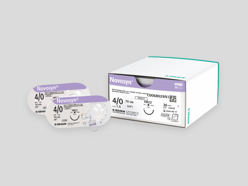 Product display for Novosyn® braided, non‑absorbable suture material, with a green information panel on the left and product packaging on the right, including a white box and several individually wrapped suture packs.