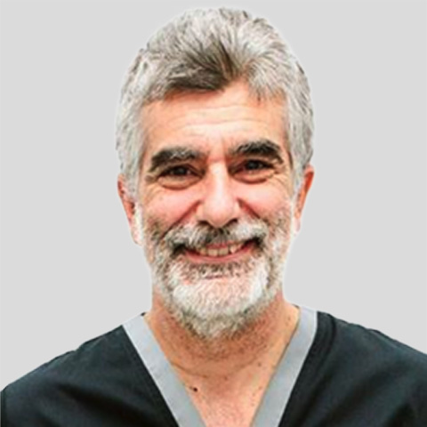 Portrait photo showing an upper-body view of a person wearing dark medical scrubs against a light background.